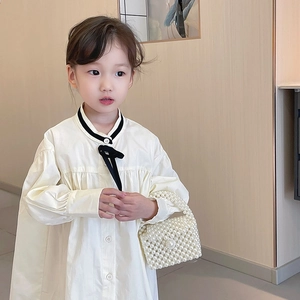 Girl in white long-sleeved cotton dress with black bow and pearl beaded handbag