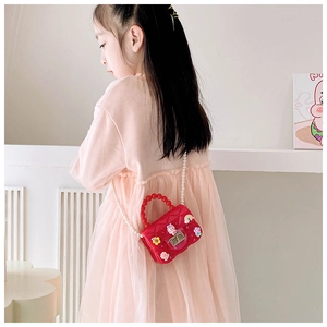 Rear view of a girl wearing a red mini jelly bag with flower charms and pearl strap