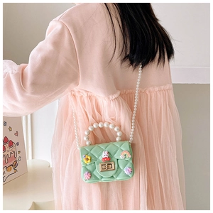 Detail of mint green quilted jelly bag with pearl handle and cartoon charms on kids