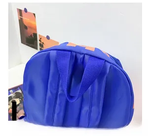 Detail of royal blue nylon backpack showing the sturdy handle and orange letter print