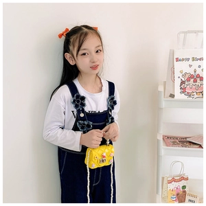 Detail of yellow quilted mini bag for kids with pearl strap and cute bunny charms