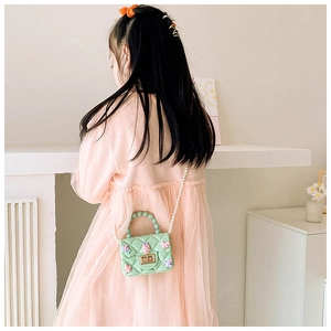 Dettaglio mini borsa trapuntata verde menta con tracolla di perle su una bambina
