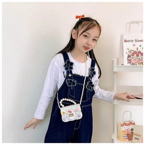 Detail of white quilted bunny crossbody bag with pearl handle worn by a child model