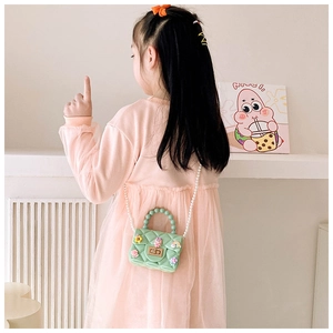 Detail of mint green jelly bag with pearl strap and cute cartoon charms on a model