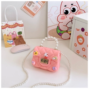 Close-up of pink silicone mini bag with pearl handle and cute cartoon rabbit charms