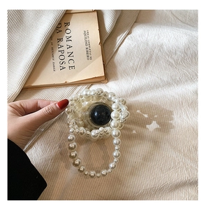 Detail of handcrafted white pearl beaded woven crossbody bag for girls on vintage book