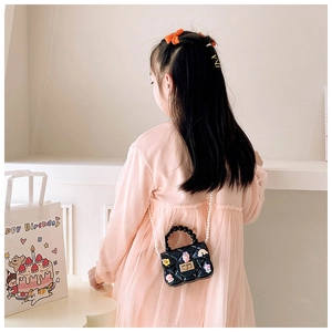 Girl wearing black cartoon quilted jelly bag with floral charms and pearl chain strap