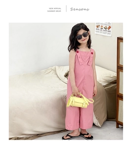 Gros plan du combishort rose pour fille avec boutons rouges et accessoires d'été