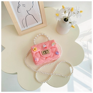 Close-up of girls' pink silicone crossbody bag with pearl handle and cartoon charms