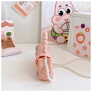 Dettaglio borsa in silicone rosa con motivo trapuntato e manico in perle