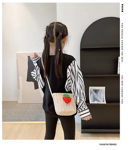 Detail of children's woven straw crossbody bag with decorative red strawberry patch