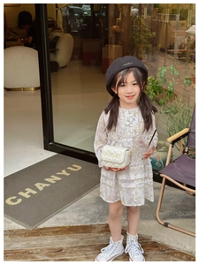 Close-up of girls mini quilted crossbody bag with gold chain strap and floral dress detail