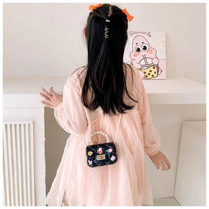 Close-up of a child black quilted crossbody bag with pearls and cute rabbit charms