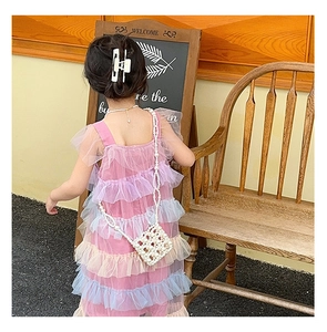 Detail of a girl wearing a tiered tulle dress with a white pearl crossbody bag