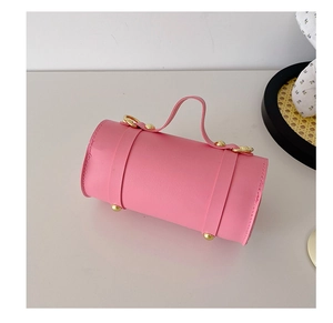 Vue détaillée du sac à main cylindrique rose avec rivets dorés et poignée