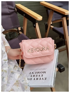 Close-up of pink quilted girls crossbody bag with gold logo and metal chain strap
