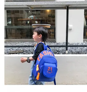 Kid wearing blue canvas preschool backpack with orange straps and 21 letter print