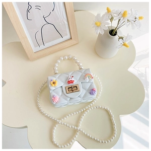 Close-up of girls mini white crossbody jelly bag with pearls and cute cartoon charms