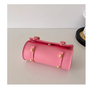 Détail du mini sac cylindrique rose avec texture en cuir et rivets en métal doré