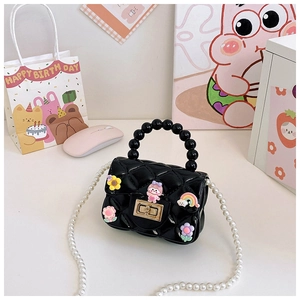 Detail of a black quilted mini jelly bag featuring colorful floral charms and pearl strap