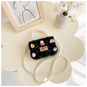 Close-up of black quilted silicone mini bag with pearl handle and colorful acrylic charms