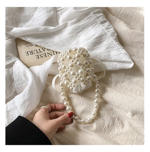 Detail of white handmade pearl beaded handbag with woven structure and pearl strap