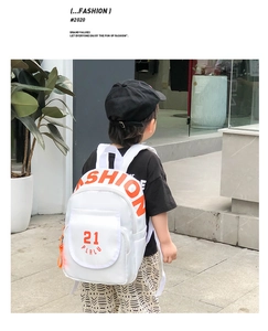 Detail of white canvas kindergarten backpack with orange Fashion lettering on the back