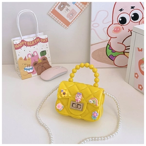 Macro shot of yellow quilted jelly bag with floral charms and pearl chain strap