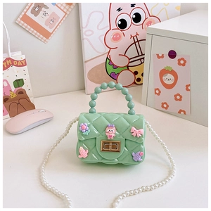 Dettaglio borsa in silicone verde menta con ciondoli cartoon e tracolla in perle
