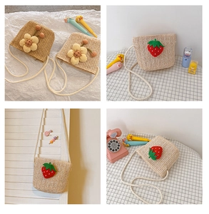 Detailed close-up of straw woven crossbody bags with floral and strawberry decor