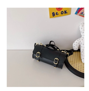 Détail du mini sac cylindrique noir pour fille avec boucles dorées et poignée haute