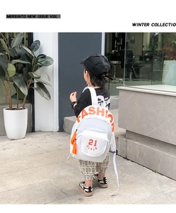 Close-up of white canvas toddler backpack featuring orange FASHION lettering and front pocket