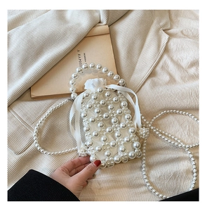 Detail of beaded pearl bucket bag featuring satin drawstring liner and chain strap
