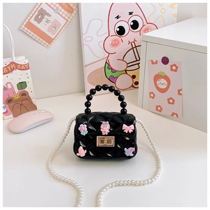 Dettaglio mini borsa trapuntata nera con catena di perle e ciondoli a forma di cartone