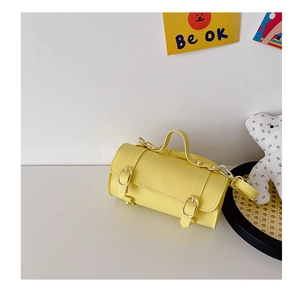 Détail du sac cylindrique jaune avec boucles dorées et texture en similicuir lisse