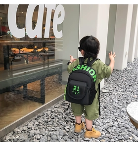 Detail of children's black canvas backpack featuring neon green fashion lettering and prints