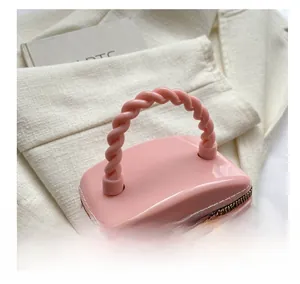 Close-up of pink mini crossbody bag with rivet texture and twisted handle detail