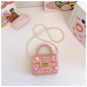 Dettaglio mini borsa in silicone rosa con motivo trapuntato, charms e perle bianche