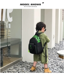 Detail of black kids backpack with neon green SHION letters and hanging strap detail