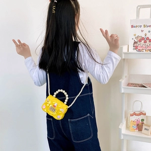 Yellow girl's quilted silicone crossbody bag with pearls and cartoon charms on a model