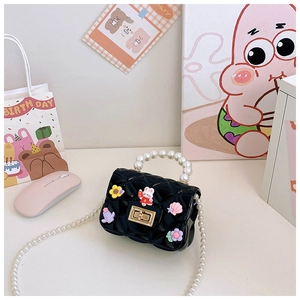 Detail of black jelly crossbody bag with pearl handle and cartoon charms on flap