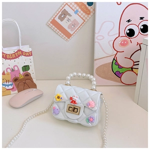 Detail of white quilted mini bag with pearl handles and colorful cartoon charms