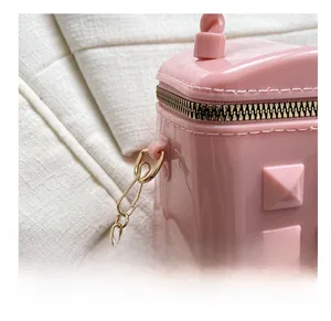 Close-up of pink jelly bag featuring pyramid studs and shiny golden metal hook chain