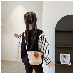 Toddler summer straw crossbody bag with red strawberry detail shown on child model