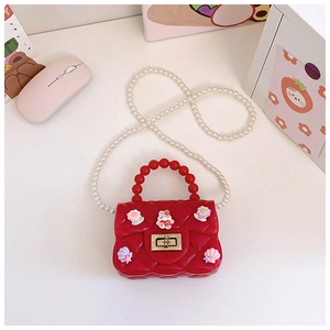 Dettaglio borsa bimba in silicone rosso con trama a rombi, ciondoli e tracolla di perle