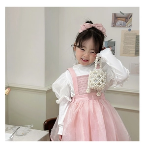 Detail of pink tutu skirt and white ruffled top with matching pearl woven handbag