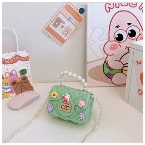 Detail of mint green quilted jelly bag with pearl handle and cute cartoon charms