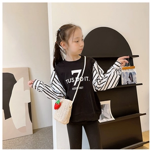 Detail of a mini strawberry straw crossbody bag paired with a striped sleeve sweatshirt