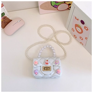 Dettaglio mini borsa bianca trapuntata con manico di perle e ciondoli a cartone animato