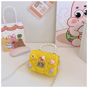 Detail of yellow quilted kids handbag with pearl handle and cartoon charms